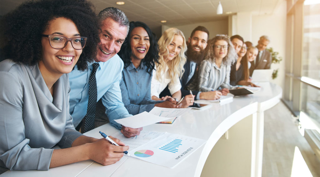 photo of a long row of happy looking diverse employees sitting next to one another