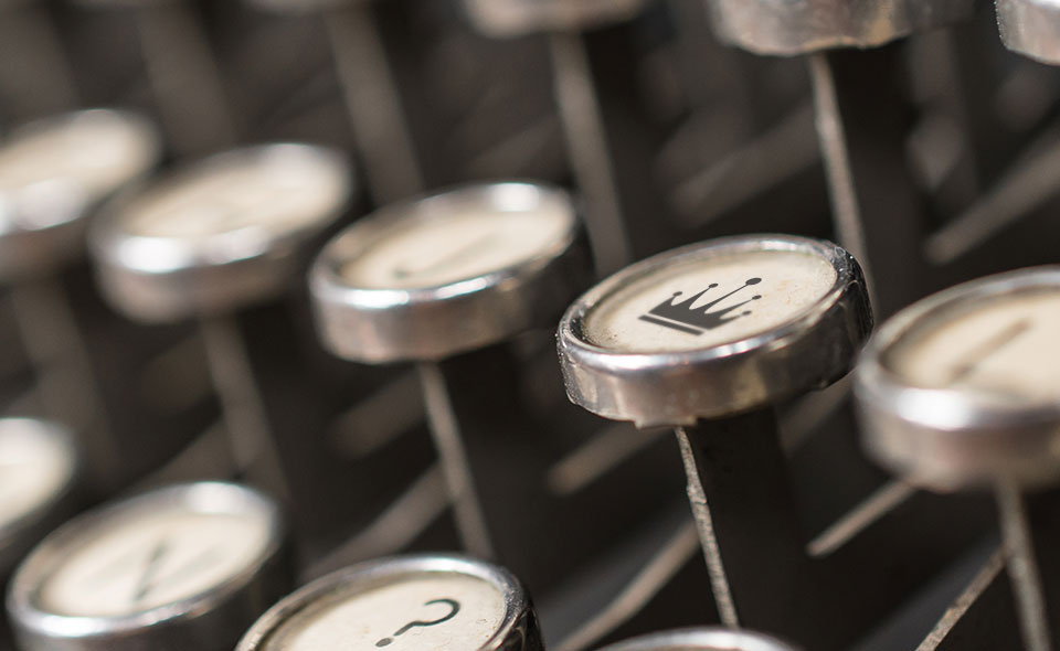Picture of a typewriter with a crown and question mark as keys.