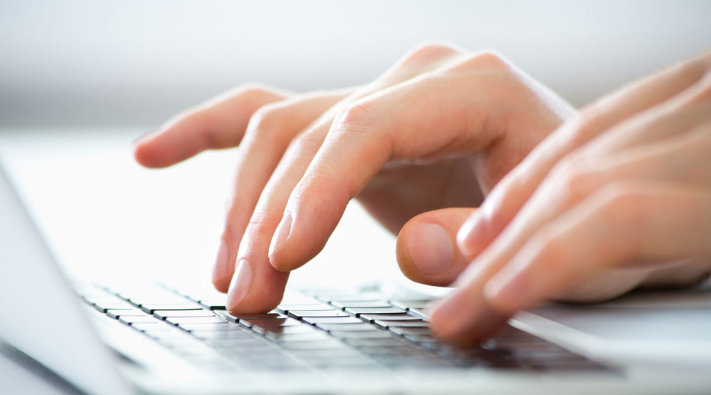 photo of a woman's hands typing on a keyboard