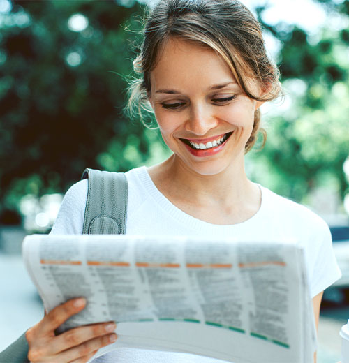 woman-reading-newspaper smiling woman looking for a job in the classified section of a newspaper